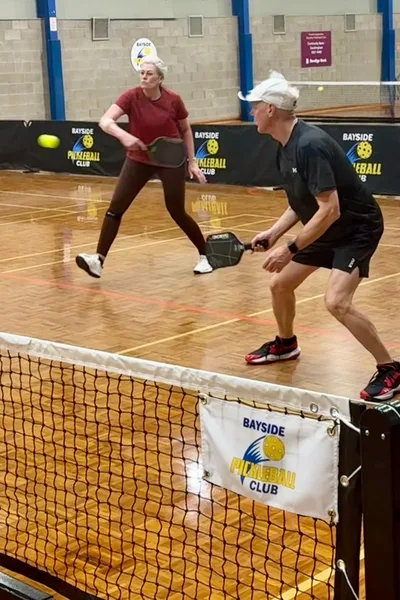 Two Bayside players ready to return a pickleball at the net